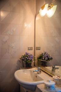 a bathroom with a sink and a mirror and flowers at casa Archiottu in Carloforte +13 photos