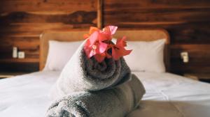 a towel animal with a flower on its back sitting on a bed at Kayu Cottage in Gili Trawangan