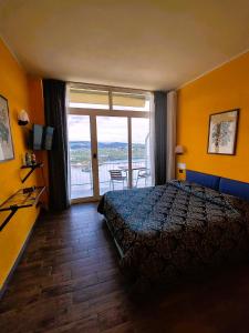 Hotel Panoramico lago d'Orta في Madonna del Sasso: غرفة فندقية بسرير ونافذة كبيرة