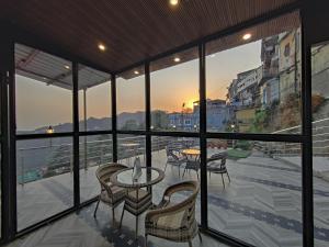 a balcony with tables and chairs and a view of a city at Sangam by Stotrak, Jhula Ghar Mussoorie in Mussoorie