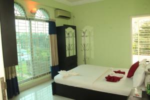 a bedroom with a bed with white sheets and red pillows at Grand Selim Resort & Tour – GSRT in Sreemangal