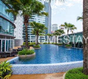 uma grande piscina com palmeiras e edifícios em Vortex KLCC Suites by Homestay em Kuala Lumpur