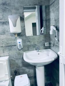 a bathroom with a sink and a toilet and a mirror at Hostel Heimli in Prishtinë