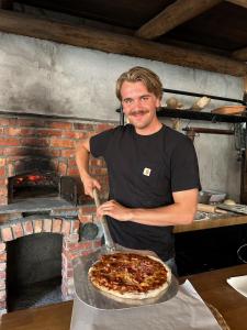 Ein Mann bereitet eine Pizza mit einem Spatel vor. in der Unterkunft Orkla Camping in Orkanger