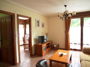ein Wohnzimmer mit einem TV und einem Tisch in der Unterkunft Apartamento Remoña 2 in Espinama