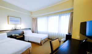 um quarto de hotel com duas camas e uma televisão de ecrã plano em South Pacific Hotel em Hong Kong