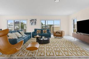 sala de estar con sofá azul y TV en Seaside Bliss with Ocean Views, en Catherine Hill Bay