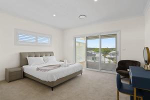 Habitación blanca con cama y balcón. en Seaside Bliss with Ocean Views, en Catherine Hill Bay