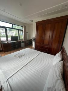 a bedroom with a large white bed with wooden cabinets at GOLDEN LAND HOTEL in Cat Ba