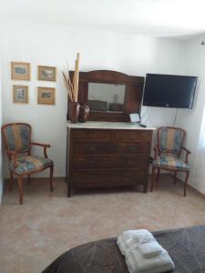 a bedroom with a dresser with a mirror and two chairs at Rifugio RoccaSerena in Rocca di Cave