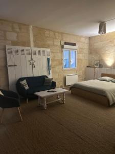 a bedroom with a bed and a couch and a table at La Beycheliere in Saint-Julien-Beychevelle
