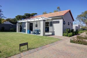 a small white building with a sign in the grass at Cozy retreat in Fourways in Johannesburg