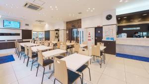 Toyoko Inn Shin-Osaka-eki Higashi-guchi في أوساكا: مطعم به طاولات وكراسي ومنضدة