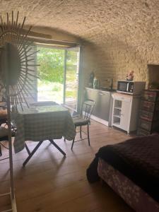 a room with a table and a kitchen with a window at Voute des anges type loft sans cloison in Castelnau-Montratier