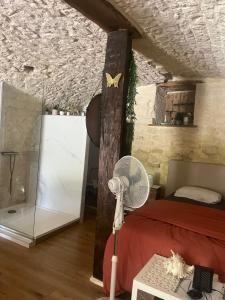 a bedroom with a bed and a fan in a room at Voute des anges type loft sans cloison in Castelnau-Montratier