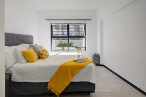 a bedroom with a bed with a yellow blanket on it at Cozy retreat in Fourways in Johannesburg