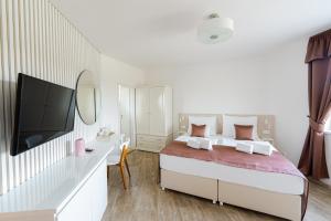 a white bedroom with a bed and a television at Penzion Uno in Zlín