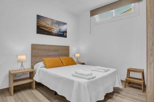a white bedroom with a bed and two tables at Casa Sol de Conil in Conil de la Frontera +17 photos