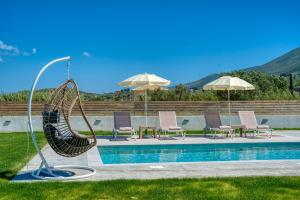 a pool with a swing and some chairs and umbrellas at Villa La Luna in Pigadhákia