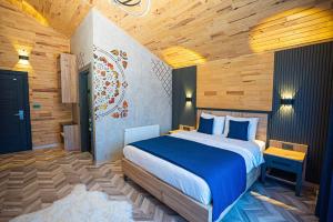 Abant Sedir Park Butik Otel في بولو: غرفة نوم بسرير وملاءات زرقاء وجدران خشبية