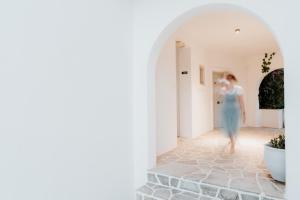a woman in a blue dress walking down a hallway at Sunrise Paros by Mr and Mrs White in Naousa