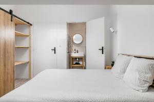ein weißes Schlafzimmer mit einem Bett und einem Spiegel in der Unterkunft COCON - Appartement neuf et confort in Saint-Étienne