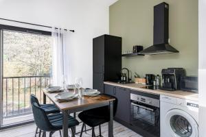 eine Küche mit einem Tisch mit Stühlen und einer Waschmaschine in der Unterkunft COCON - Appartement neuf et confort in Saint-Étienne