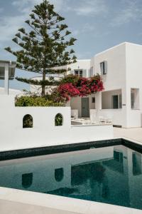 a swimming pool in front of a house with a tree at Sunrise Paros in Naousa