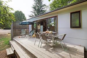 a deck with a table and chairs and an umbrella at Huttopia Etang Fouché in Arnay-le-Duc