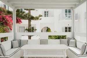 a white porch with white furniture and pink flowers at Sunrise Paros in Naousa