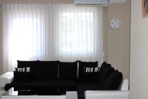 een woonkamer met een zwart-witte bank en een klok bij Oasis in Struga