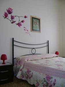 ein Schlafzimmer mit einem Bett mit Blumenarrangement an der Wand in der Unterkunft La Camelia in Riposto