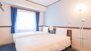 a bedroom with two beds and a window at Toyoko Inn Shin-Osaka-eki Higashi-guchi in Osaka