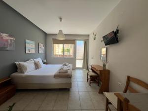 a bedroom with a bed and a television in it at Artemis Rooms - Beach at Your Doorstep in Platanias