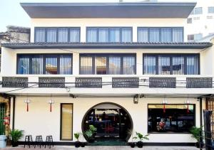 a white building with an archway and windows at Caiyong Hometel & Cafe's Studio in Khlong San