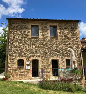 Una vieja casa de piedra con una toalla en una valla en Agriturismo Alchimista, en Casole dʼElsa