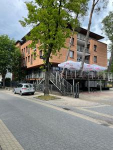 un edificio con un albero e un'auto di fronte di Apartament Planeta 209 a Mielno