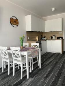 una cucina con un tavolo bianco e sedie bianche di Apartament Planeta 209 a Mielno