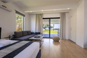 a bedroom with a bed and a couch and a table at RLM Prime Beach Panoramic Villa in Kolimbia +42 photos