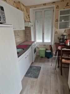 une cuisine avec des armoires blanches, une table et un évier dans l'établissement Saint Pair sur Mer 50 m de la plage, à Saint-Pair-sur-Mer