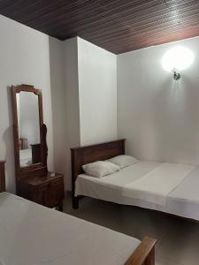 Himo Guest Inn في دهيفالا: غرفة نوم بسريرين ومرآة ومصباح