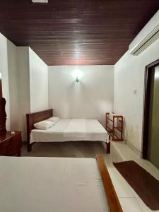 Himo Guest Inn في دهيفالا: غرفة نوم بسرير وسقف خشبي