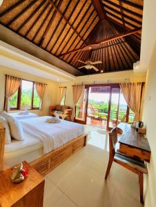 a bedroom with a large bed and a table at BUDA AMITABA in Ubud