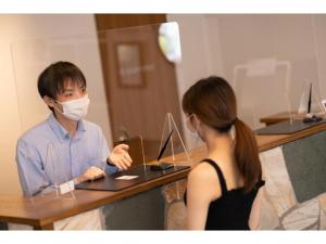 un homme et une femme dans un masque travaillant sur un ordinateur portable dans l'établissement Hotel Emit Shibuya - Vacation STAY 40894v, à Tokyo