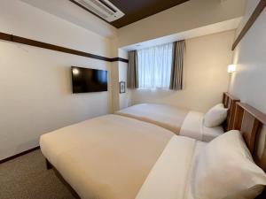 Cette chambre comprend deux lits et une télévision. dans l'établissement Hotel Emit Shibuya - Vacation STAY 40894v, à Tokyo