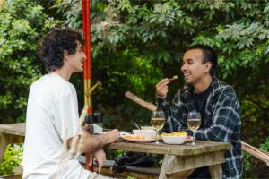 dos hombres sentados en una mesa de picnic comiendo comida en Tranquility, en Owaka
