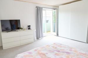 a white bedroom with a tv and a bed at Zimmervermietung Jäger in Bregenz +4 photos
