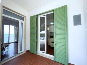 Camera con porte scorrevoli verdi e balcone. di Villa Porticciolo - ArgonautiVacanze a Rio Marina