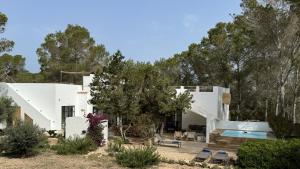 una casa bianca con piscina e alberi di Feliz Lagartija a Cala Saona