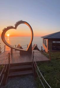 una terraza de madera en forma de corazón con una casa y la puesta de sol en Günbatımı Bungalov, en Rize